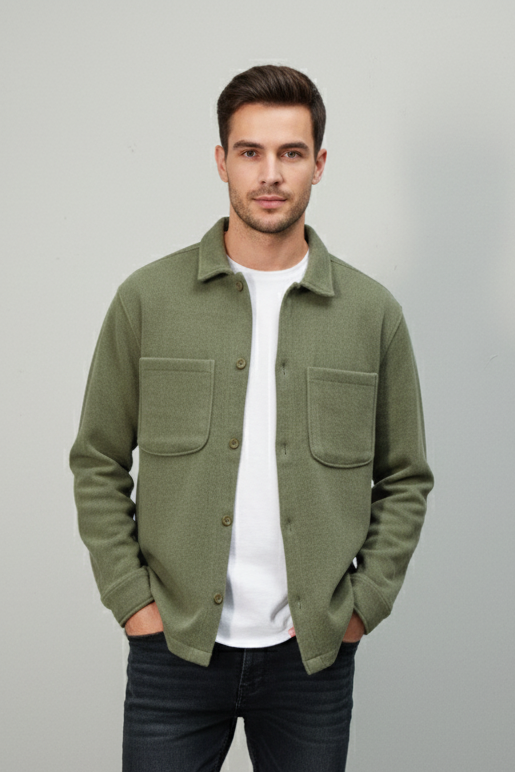 Man wearing a green shacket, white shirt and black jeans on a gray background