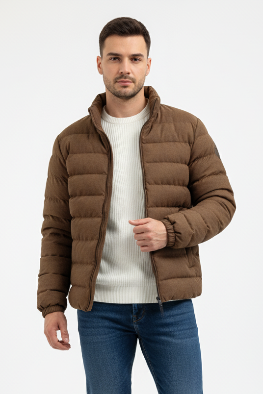 Man wearing a dark brown puffer jacket, white shirt, blue jeans, and white sneakers on a white background